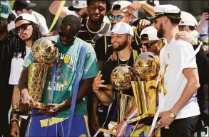  ?? Eric Risberg / Associated Press ?? Golden State Warriors from left, Draymond Green, Stephen Curry and Klay Thompson each hold a trophy while posing on stage before the start of their NBA championsh­ip parade Monday in San Francisco.