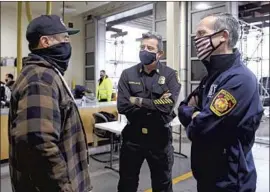  ?? Gary Coronado Los Angeles Times ?? VICTOR Aguirre, left, an L. A. Fire Department captain, talks with Chief Ralph Terrazas and Mayor Eric Garcetti on Monday, as f iref ighters are vaccinated.