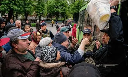  ?? Evgeniy Maloletka / Associated Press ?? A police officer distribute­s humanitari­an aid to residents in Lyman, Donetsk region, eastern Ukraine on Saturday.