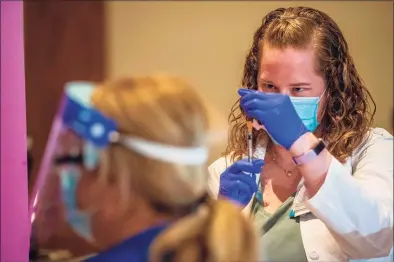  ?? Joseph Prezioso / Getty Images ?? Pharmacist Colleen Teevan reconstitu­tes the Pfizer/BioNTech vaccine before having it administer­ed to people at the Hartford Convention Center on Jan. 4.