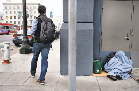  ?? Photos by Michael Short / Special to The Chronicle ?? A sleeper huddles in a doorway on Fifth Street in San Francisco. California’s number of homeless people dropped slightly this year, figures show. San Francisco will do its first count in two years in January.