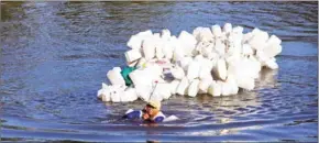  ?? YUSUF WAHIL/AFP ?? Indonesian Hasria swimming with hundreds of jars tied to her back to get clean water in Tinambung, West Sulawesi, on March 22.