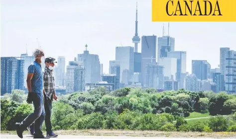  ?? PETER J THOMPSON / FOR NATIONAL POST ?? Pedestrian­s in masks walk along Toronto’s Broadview Avenue on Tuesday. The Toronto area has been hit much harder than elsewhere in Ontario.