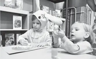  ??  ?? Siblings MaKaela Partridge, 3, left, and Griffin Partridge, 18 months, color during craft time at the Anne Arundel County Public Library, which hosted a Halloween story time Wednesday morning at its Westfield Annapolis Mall location.