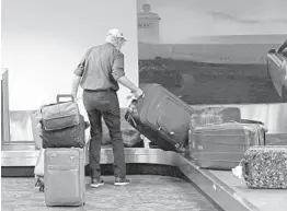  ?? JOHN MCCALL/SOUTH FLORIDA SUN SENTINEL ?? A traveler from New York picks up luggage on Wednesday in Terminal 2 at Fort Lauderdale-Hollywood Internatio­nal Airport.