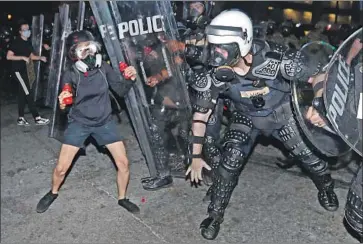  ?? John Bazemore Associated Press ?? ATLANTA police clash with a protester at a rally against police brutality. Across the U.S., images of tanks and armed troops in city streets and injured protesters and journalist­s told of a nation at conf lict with itself.