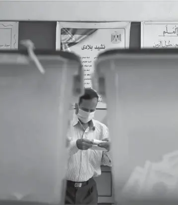  ?? AHMED HASAN/AFP VIA GETTY IMAGES ?? An Egyptian man prepares to cast his ballot during the second phase of a parliament­ary election Saturday in Cairo.