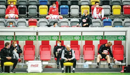  ?? SASCHA SCHUERMANN/AFP/DFL ?? SESUAI DENGAN PROTOKOL: Bench Fortuna Duesseldor­f menerapkan aturan jaga jarak dalam laga melawan SC Paderborn 07 di Merkur-Spiel Arena (16/5). Hal yang sama dilakukan pelatih Red Bull Leipzig Julian Nagelsmann (foto paling bawah) serta dua pemain VfL Wolfsburg, striker Daniel Ginczek (kiri) dan bek Kevin Mbabu.