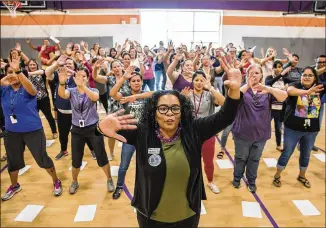  ?? PHOTOS BY RICARDO B. BRAZZIELL / AMERICAN-STATESMAN ?? Leah Mercer, assistant principal intern at Newton Collins Elementary, leads the staff in a spirit chant before profession­al developmen­t in the new school’s gym. Collins is believed to be the first modern school in Central Texas named for a former slave.