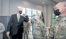  ?? ALYSSA STONE/THE ENTERPRISE, POOL PHOTO ?? Gov. Charlie Baker elbow bumps Massachuse­tts National Guard Capt. Wendy Letchworth of Maine during a tour of the COVID-19 vaccinatio­n site at The Shaw's Center in Brockton on Wednesday.