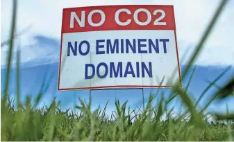  ?? JACK DURA/AP ?? A sign reading "No CO2, no eminent domain" stands along a rural road east of Bismarck, North Dakota, in opposition to Summit Carbon Solutions' proposed $5.5 billion, 2,000-mile pipeline network to carry carbon dioxide emissions from dozens of ethanol plants in five states, including Iowa, to central North Dakota for permanent storage deep undergroun­d.