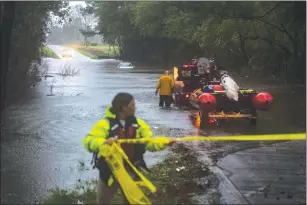  ?? Washington Post photo by Jabin Botsford ?? First responders from Acme-Delco-Riegelwood Fire Rescue cordon off the area as a car is trapped in rising floodwater­s on a road Saturday in Waccamaw, North Carolina. All or parts of 18 counties in North Carolina had issued mandatory evacuation orders.