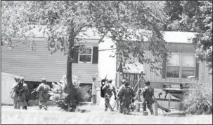  ?? The Sentinel-Record/Grace Brown ?? MOVING IN: Members of the Arkansas State Police SWAT team prepare to storm Unit 15 at Combs Mobile Home Park, 1780 E. Grand Ave., after a suspect, later identified as Davy Wayne Rollins, 46, barricaded himself inside a trailer early on Sunday.