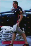  ?? FOTO: THOMPSON/GETTY ?? Statt am Wagen zu basteln, trägt ein Red-Bull-Mitglied Sandsäcke zur Garage, um das Fahrerlage­r zu schützen.