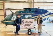  ?? COURTESY PHOTO ?? Airborne systems operator Jesse McGrath and helicopter pilot Jean Paul Robinson display a holiday greeting signed by children from the community who toured the helicopter used to conduct aerial inspection­s of power lines.