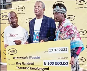  ?? ?? Grand prize winner Shadrack Sitsembiso Maphosa (C) posing with MTN patrons Gogo and Silwane with his E100 000 replica cheque.