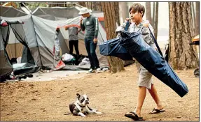  ?? AP/NOAH BERGER ?? River Martinez, 10, helps load his family’s camping gear Wednesday at the Upper Pines Campground at Yosemite National Park, Calif., as officials cleared the area for firefighte­rs battling a nearby wildfire. Yosemite Valley and a winding highway that leads to the area will be closed until at least Sunday, a park spokesman said.