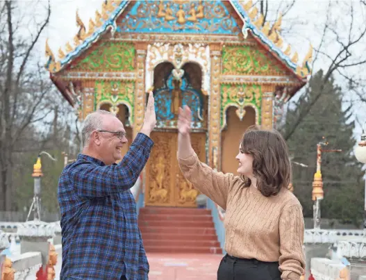  ?? DORAL CHENOWETH, DORAL CHENOWETH/DISPATCH ?? Steve Huggins and his daughter Betsy Huggins celebrate with a high-five at the Watlao Buddhamama­karam, 3624 Bexvie Ave., on the East Side. The Buddhist Temple was the answer to Riddle No. 9 in Joe's Mildly Entertaini­ng Easter Egg Hunt.