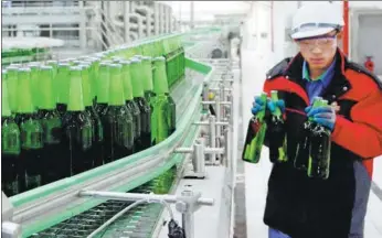  ?? PROVIDED TO CHINA DAILY ?? A supervisor picks some bottles of beer for quality tests at Tsingtao’s production base in Luoyang, Henan province.
