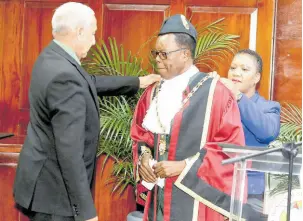  ?? PHOTO BY NATHANIEL STEWART ?? Clarendon Municipal Corporatio­n Winton Maragh, councillor of the Rocky Point division and former mayor of May Pen, is assisted by Nidine Lopez, acting director of administra­tion at the Clarendon Municipal Corporatio­n (CMC), to robe Joel Williams, councillor of the Denbigh division, as he is installed as the mayor of May Pen, during a ceremony yesterday at the CMC.