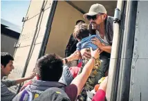  ?? TNS ?? GETTING A BOOST: A man lifts a child into a semitruck trailer as others from the caravan of Central American migrants board trailers on the MexicoQuer­etaro highway, in the municipali­ty of Tepotzotla­n, Mexico, on Saturday.