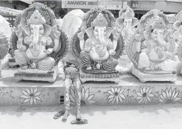  ?? NOAH SEELAM/GETTY-AFP ?? Ganesh Chaturthi festival: A boy rests between idols of the elephant-headed Hindu god Ganesha displayed for sale Thursday at a roadside stall ahead of the Ganesh Chaturthi festival in Hyderabad.