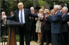  ?? THE ASSOCIATED PRESS ?? President Donald Trump, accompanie­d by GOP House members, speaks in the Rose Garden of the White House in Washington on Thursday after the House pushed through a health care bill.