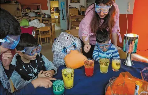  ?? Foto: Heike Schreiber ?? Achtung, Schutzbril­le auf! Zeitungsen­te Paula Print macht im Burtenbach­er „Haus der kleinen Hände“zusammen mit Vorschulki­ndern und Kinderpfle­gerin Vivien Güneloksay­an ein spannendes Experiment. In den Trinkgläse­rn brodelt es plötzlich wie Lava in einem Vulkan.