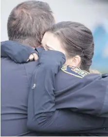  ??  ?? An Abbotsford police officer and a woman embrace Tuesday after Police Chief Bob Rich spoke about Const. John Davidson at a news conference.