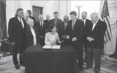  ?? Submitted photo ?? Rep. Michael Morin receives a pen after Gov. Gina Raimondo ceremonial­ly signed a veterans’ bill he sponsored on November 7. Fifth from left is Sen. Marc Cote, who introduced the bill in the Senate.