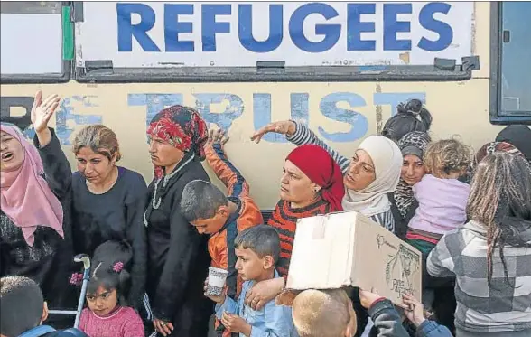  ?? MARKO DJURICA / REUTERS ?? Mujeres y niños hacen cola para recibir comida en un campo improvisad­o en Idomeni, cerca de la frontera de Grecia con Macedonia