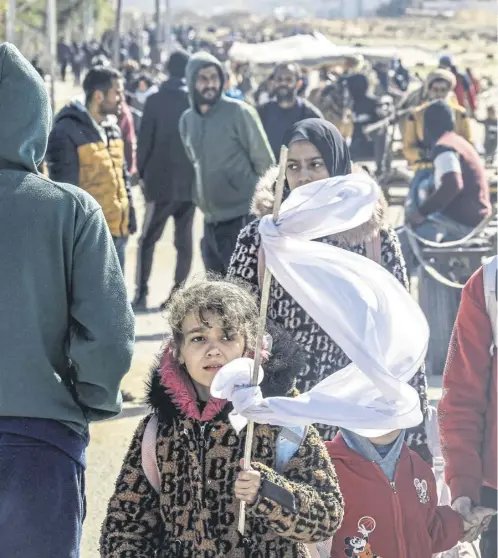  ?? ?? A girl holds a makeshift white flag as she walks with other displaced Palestinia­ns fleeing from Khan Yunis in the southern Gaza Strip amid the ongoing conflict between Israel and the Palestinia­n militant group Hamas