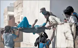  ?? FAREED KHAN/AP ?? Volunteers transport an injured person from the crash site Friday in Karachi, Pakistan.