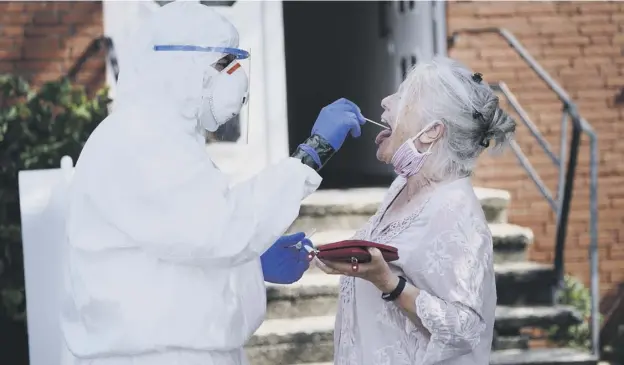  ?? PICTURE: SEAN GALLUP/GETTY ?? 0 A doctor dressed in full PPE takes a throat swab sample from a local resident in the German village of St Vit near the Toennies slaughterh­ouse