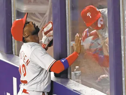  ?? KATHY WILLENS/AP ?? Phillies left fielder Andrew McCutchen tracks the path of Gio Urshela’s sixth-inning, three-run home run as Phillies catching coach Greg Brodzinski ducks in the bullpen on Monday at Yankee Stadium.