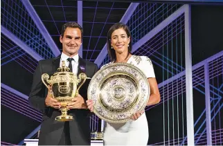  ?? AFP ?? 2017 WIMBLEDON Men’s and Women’s singles champions, Switzerlan­d’s Roger Federer (L) and Spain’s Garbine Muguruza posing with their trophies at the Champions Dinner in central London on July 16.