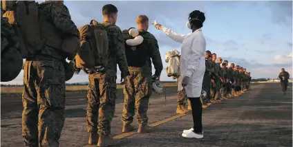  ?? JOHN MOORE/ GETTY IMAGES ?? A health worker takes the temperatur­es of U. S. troops arriving to take part in Operation United Assistance Thursday near Monrovia, Liberia. The marines landed to support the American effort to contain the Ebola epidemic.