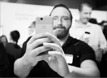  ?? ELIJAH NOUVELAGE/GETTY-AFP ?? A member of the media holds a Pixel 2 smartphone at Google’s launch The firm is working to compete with Apple.