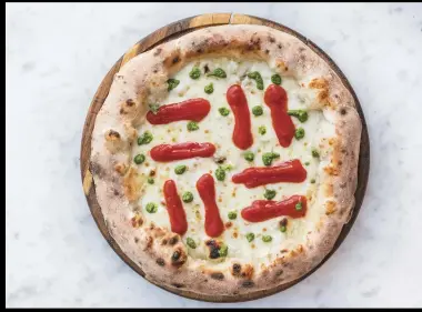  ??  ?? Pepe upends tradition with a pie translatab­le as “margherita gone wrong”: baked crust and cheese finished with reductions of tomato and basil.