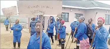  ?? (Pics: Thokozani Mamba). ?? Takhamuti Farmers Associatio­n workers in song while carrying hoes as they picket outside the sugar cane scheme offices yesterday, demanding the payment of their oustanding salaries.