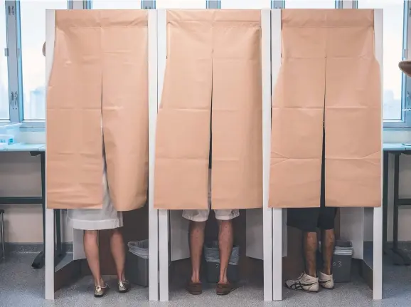  ?? LAST CALL: People prepare their votes inside booths during the second round of France's presidenti­al election at a polling station in Hong Kong. Picture: AFP ??