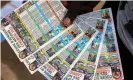  ?? Photograph: Daniel Beloumou Olomo/AFP/Getty Images ?? A vendor holds schedules for the Africa Cup of Nations in Yaoundé. Cameroon, unlike many recent hosts, has a matchgoing culture.