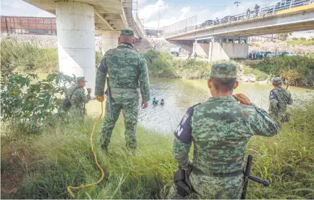  ??  ?? Elementos de la Guardia Nacional, del lado de Matamoros, y de la Patrulla Fronteriza, del lado estadounid­ense, observan a migrantes cruzar el río Bravo.