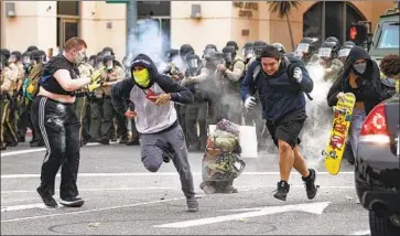  ?? Gina Ferazzi Los Angeles Times ?? DEMONSTRAT­ORS retreat as Riverside County sheriff’s deputies fire nonlethal rounds after declaring an unlawful assembly after curfew began Monday. The protests were among dozens across the nation.