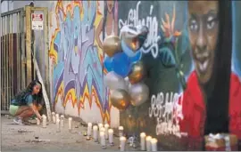  ?? Robert Gauthier Los Angeles Times ?? DEZURE STEWART lights candles at a recently painted mural of Nathesia Lewis, who was one of five people killed in a fiery car crash in Windsor Hills.