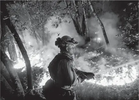  ?? Marcus Yam Los Angeles Times ?? FIREFIGHTE­R Mario Topete of Cal Fire works to prevent f lames from crossing Highway 29 north of Calistoga last week.