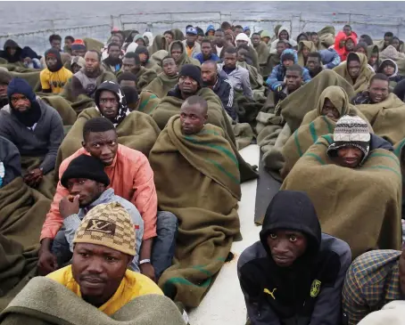  ?? ?? Migrants sit on the deck of a Belgian Navy vessel after they were saved in the Mediterran­ean Sea off the Libyan coast on June 24, 2015.