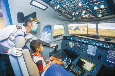  ?? RIANA SETIAWAN/JAWA POS ?? DISIPLIN PROTOKOL KESEHATAN: Petugas menemani anak di wahana simulator pilot KidZania Surabaya, Jalan Abdul Wahab Siamin, kemarin.