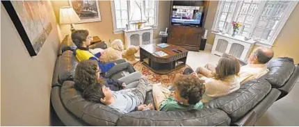  ?? KENNETH K. LAM/BALTIMORE SUN ?? The Gaarder family watches as Archbishop William Lori celebrates Mass on a live stream from Cathedral of Mary Our Queen on March 29.