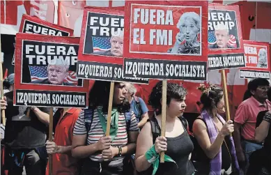  ?? MARTIN MEJIA THE ASSOCIATED PRESS ?? Protesters hold signs that read in Spanish “Get out, IMF,” and “Get out, Trump” during a march against the G20 summit.